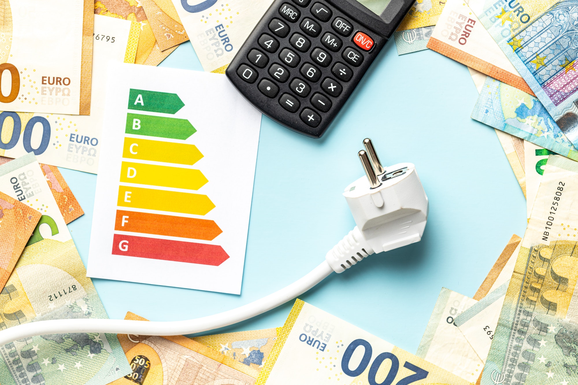 Electric plug, calculator, energy label and euro money on blue background.